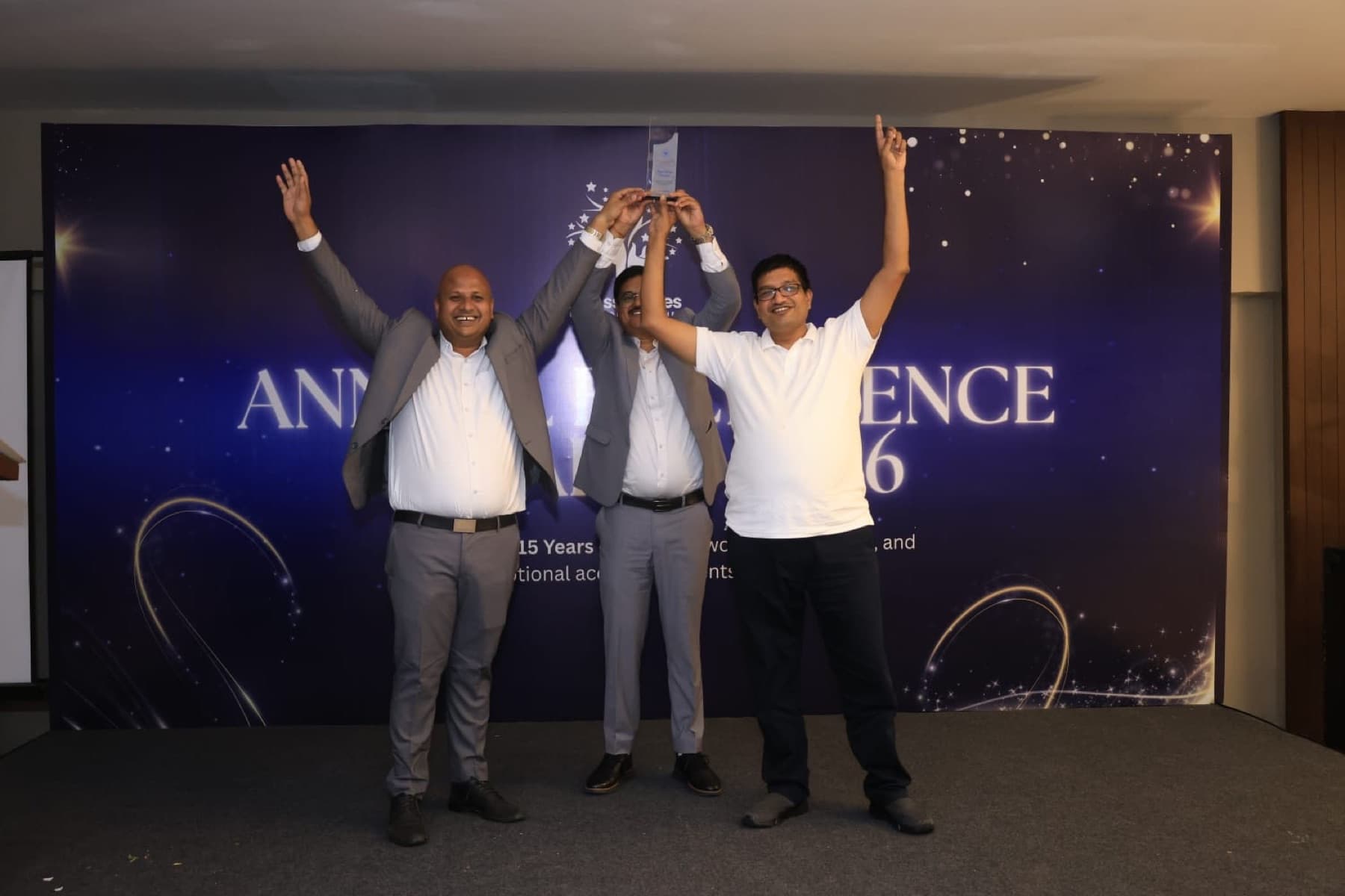 Team members raising a trophy on stage at the annual day awards