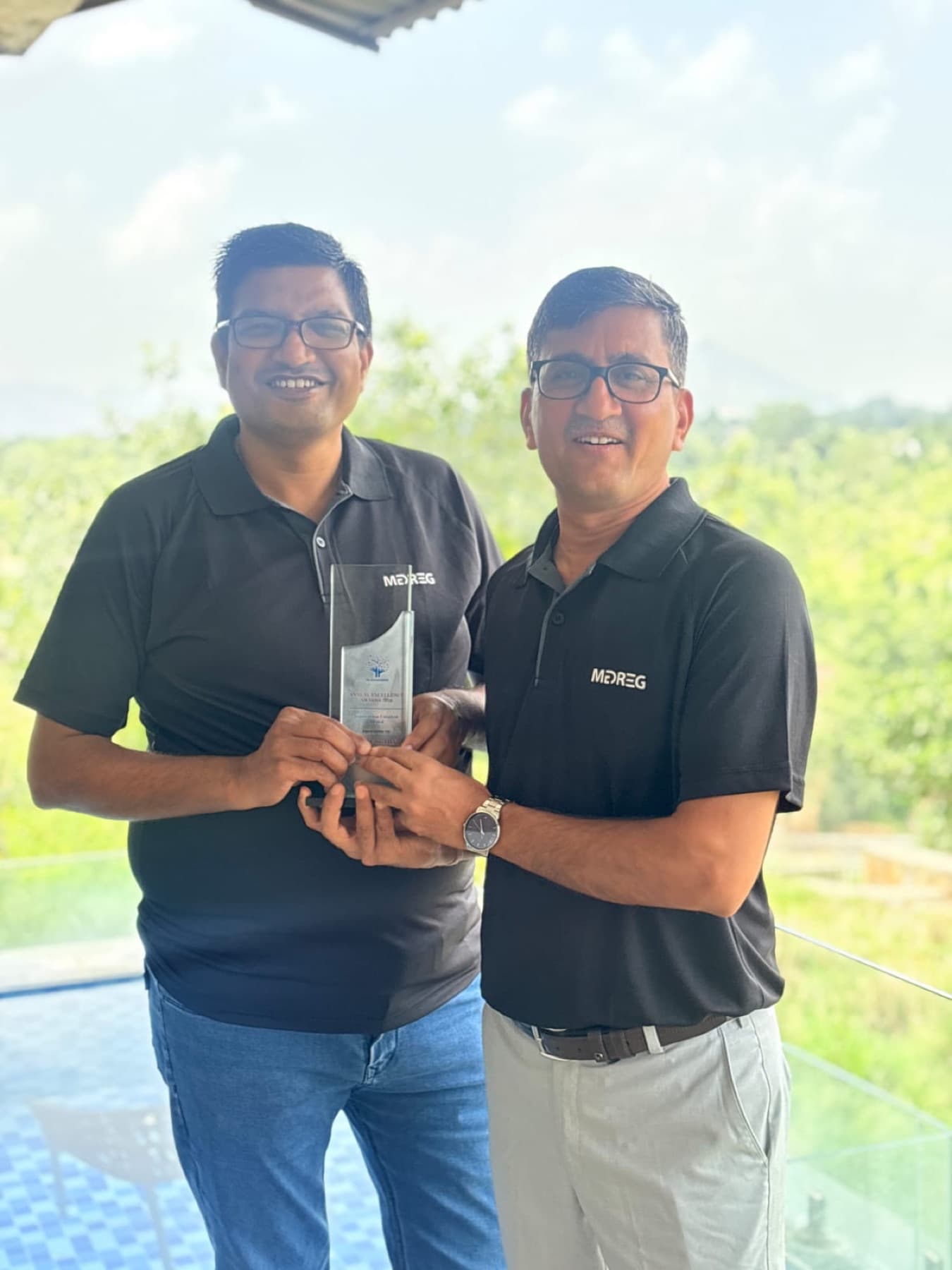 Two MedReg team members holding an award